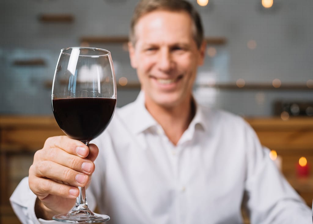 Homme tenant son verre à vin par la tige
