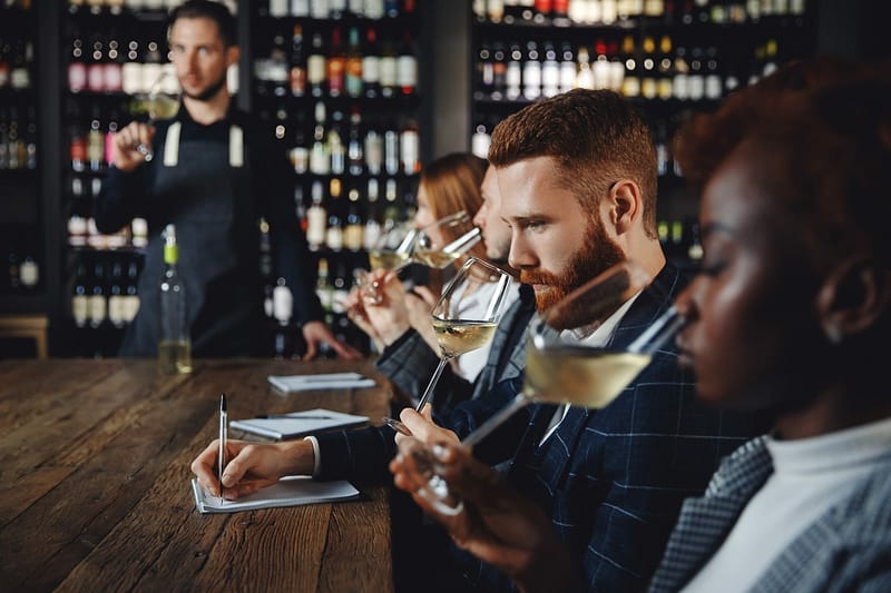 plusieurs sommeliers passant un concours et inscrivant leurs notations sur une feuille devant eux