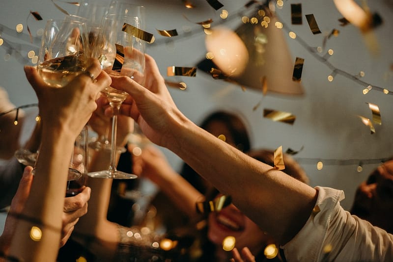 flûtes de champagne qui trinquent ensemble lors d'une fête avec plusieurs personnes et confettis