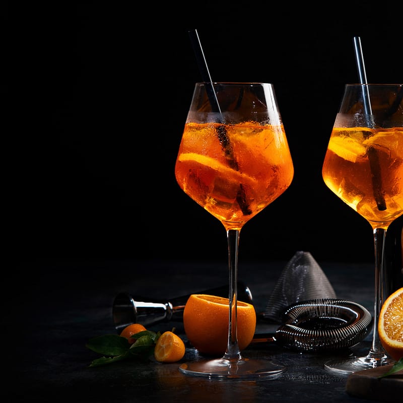 2 verres de vin orange avec des pailles et des oranges en dessous
